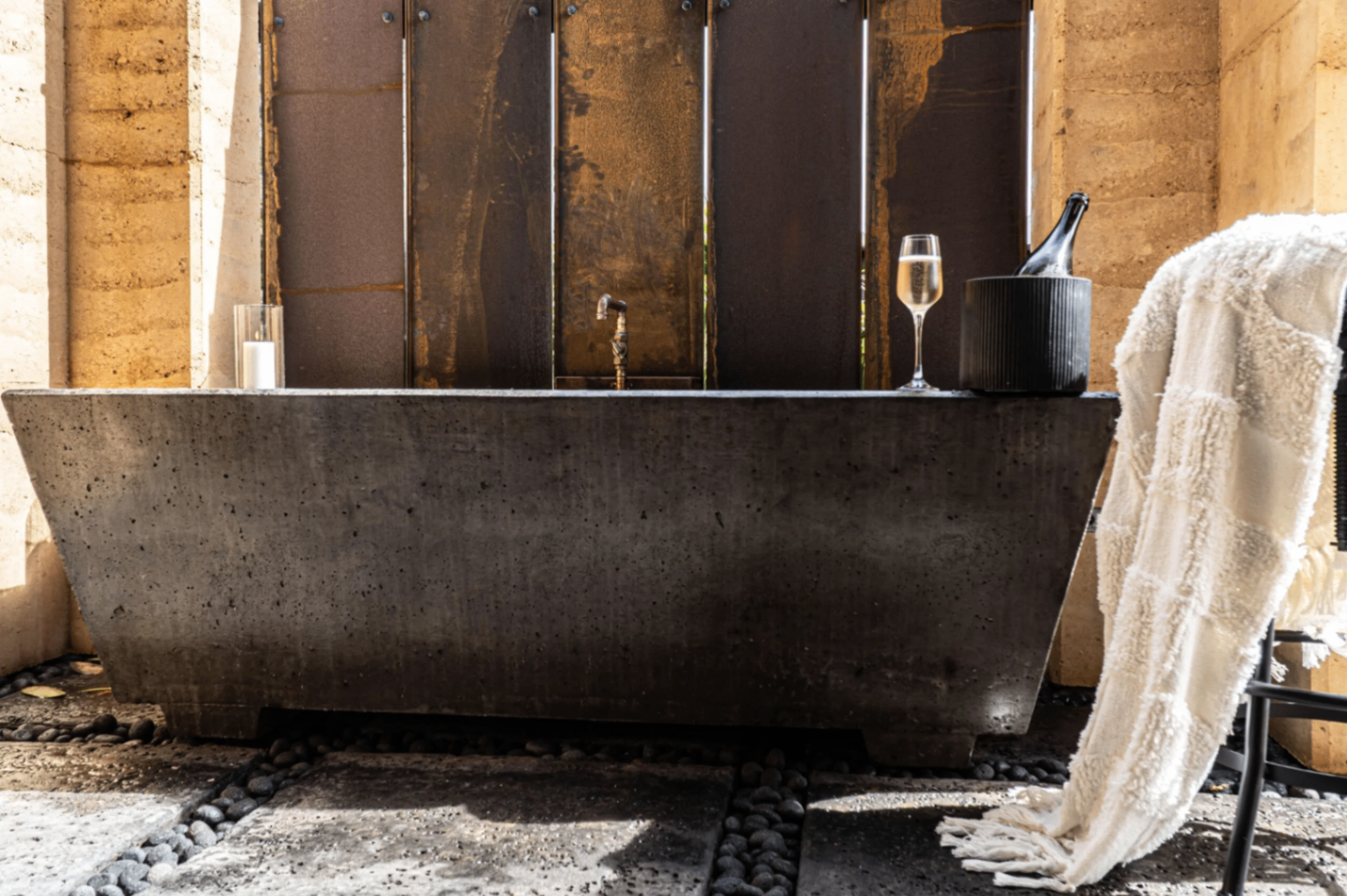 Concrete soaking tub beside rammed-earth walls