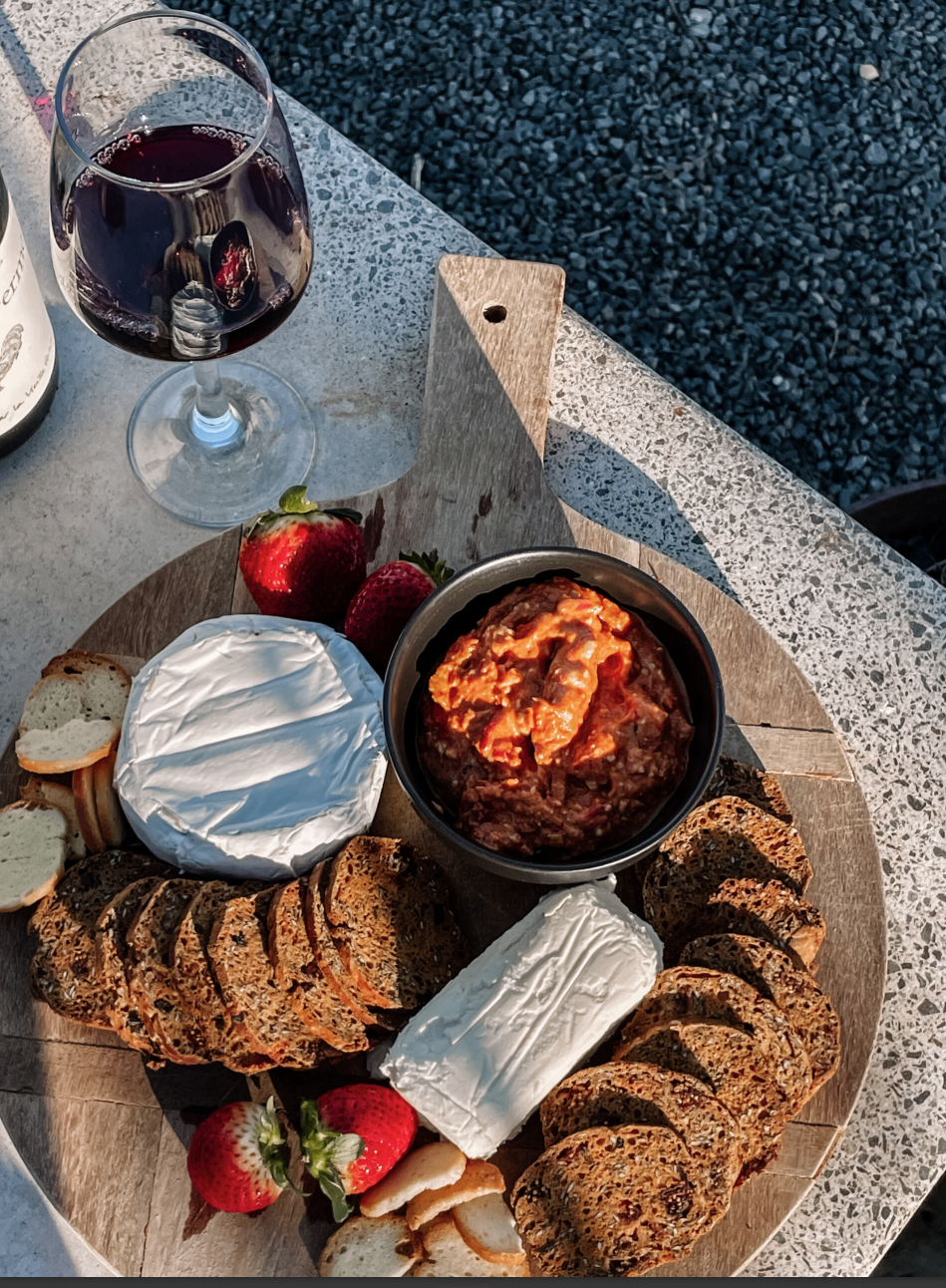Charcuterie and dips beside a glass of red at the pool