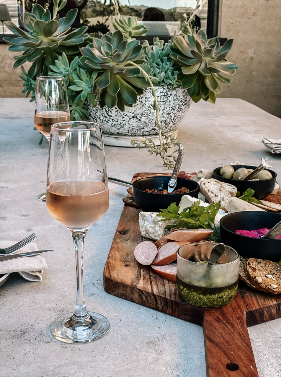 Rosé and a grazing board on the concrete table with succulents