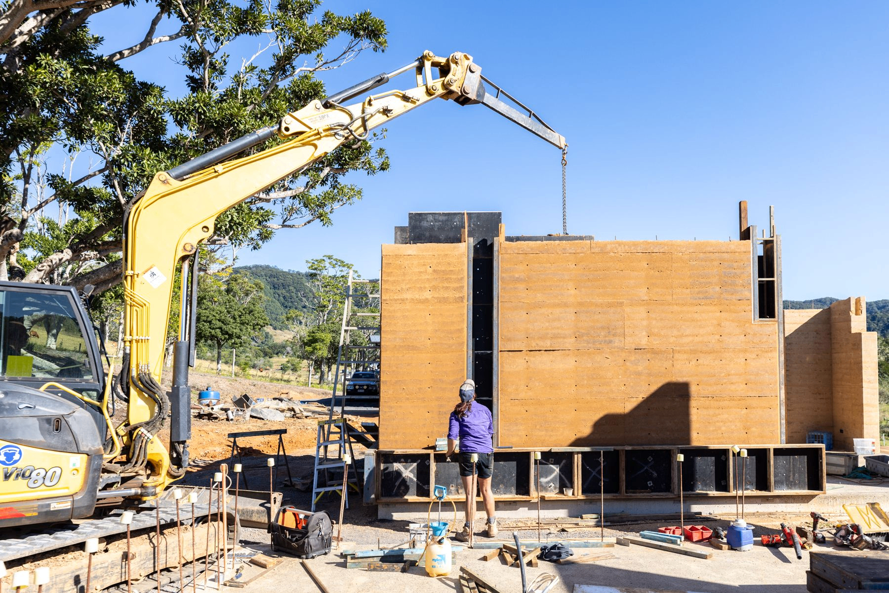 Steel formwork lifted from a finished rammed-earth wall