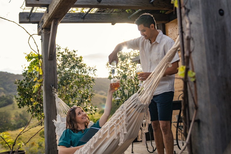 A guest pouring a drink to someone in the hammock
