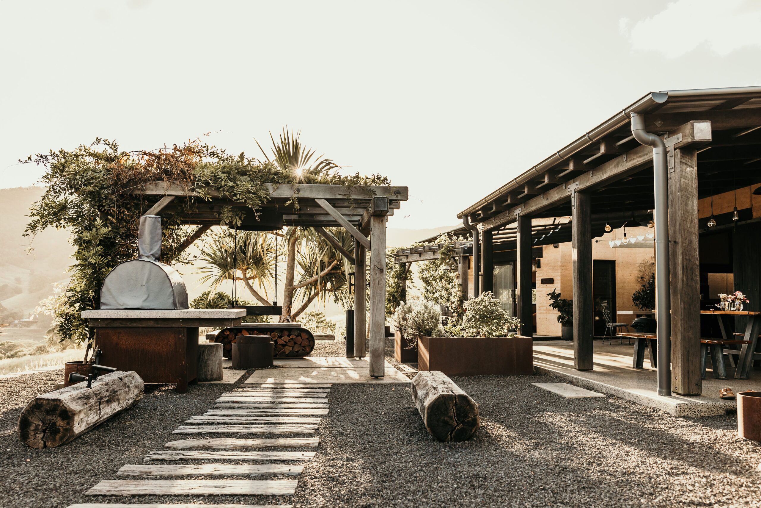 A firepit glowing at dusk with two timber stools
